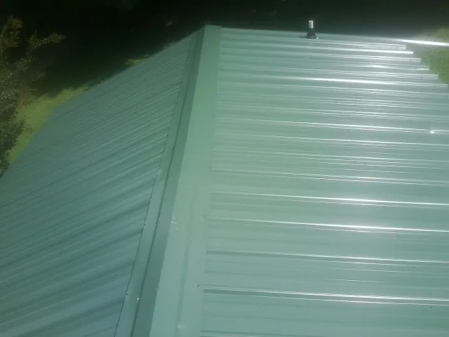 New green metal panels meeting at the ridge of a roof — Flat Roof Repair work by our crew in Allardt