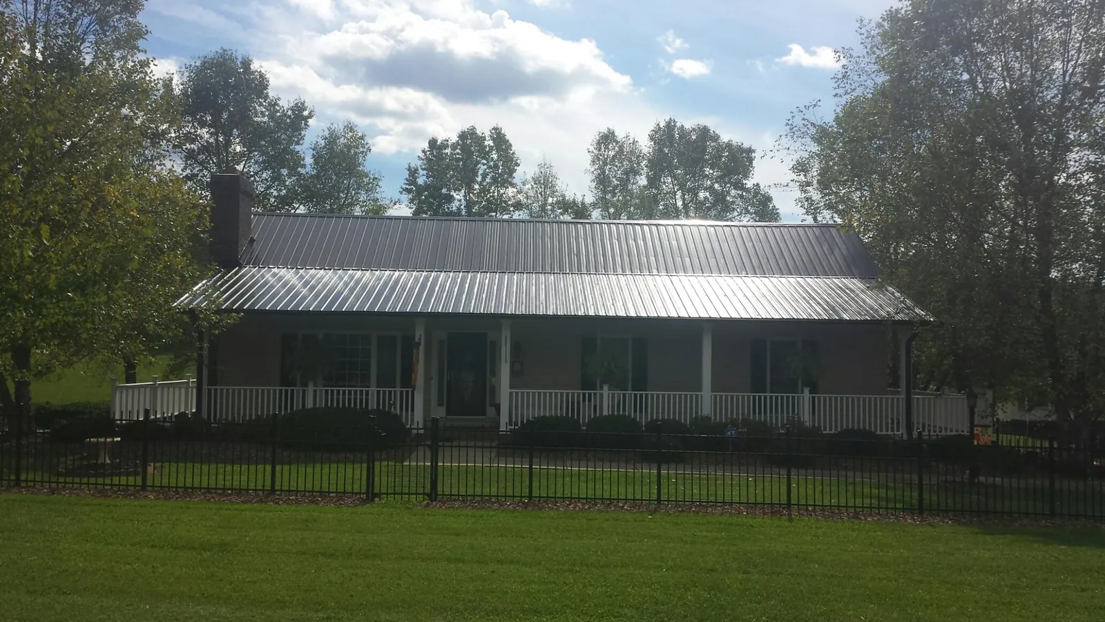 Gray metal roof on a brick ranch with a full width front porch — Gutter Guard Installation work by our crew in Allardt