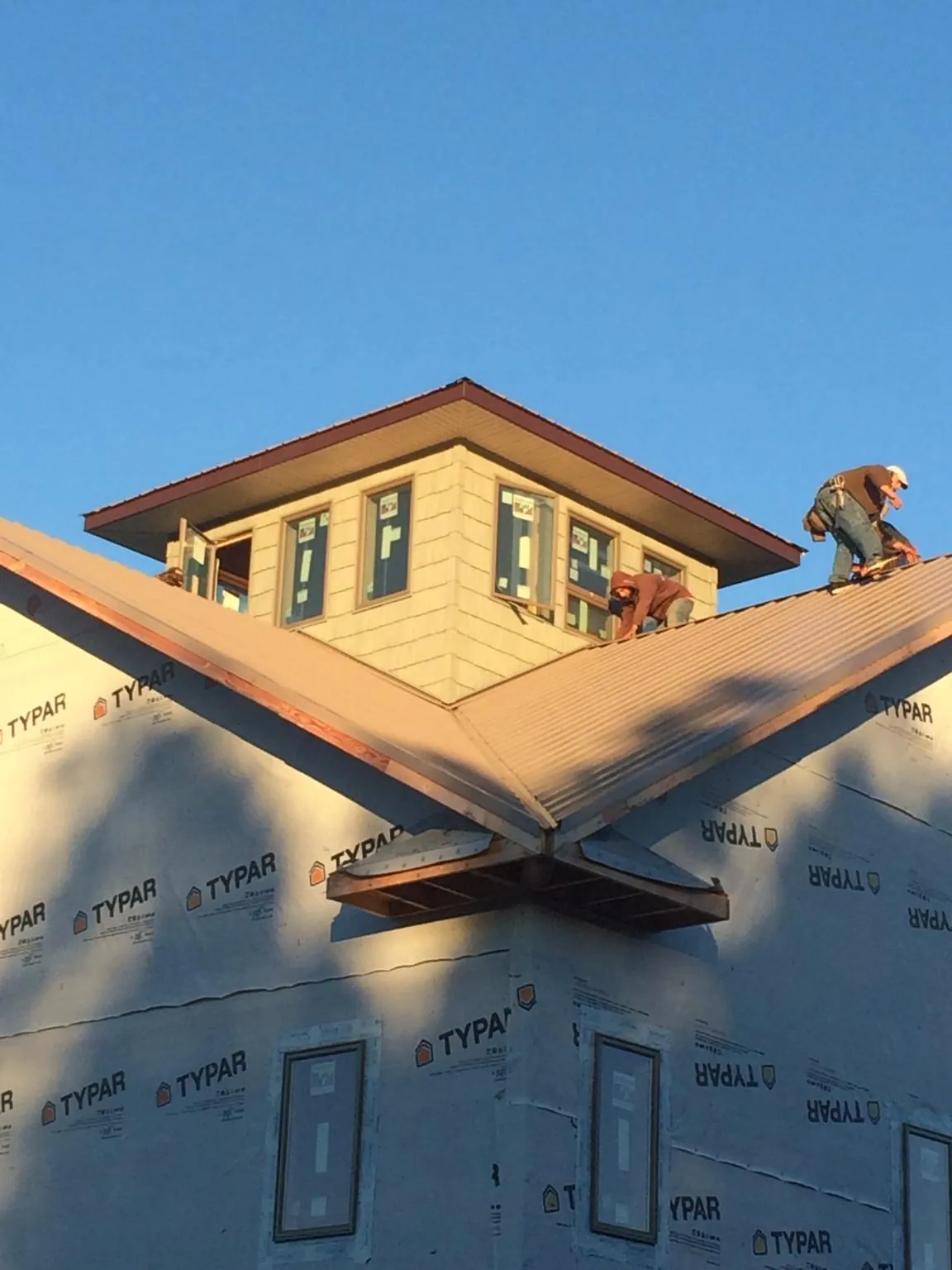 Roofers working around a rooftop cupola on a new metal roof at sunset — Roof Waterproofing in Allardt by Roofing Brothers